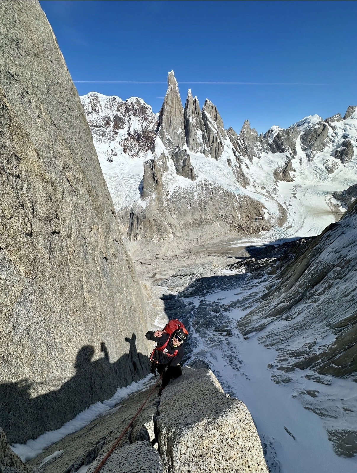 Rock climber rappelling down icy cliff face in alpine mountaineering setting
