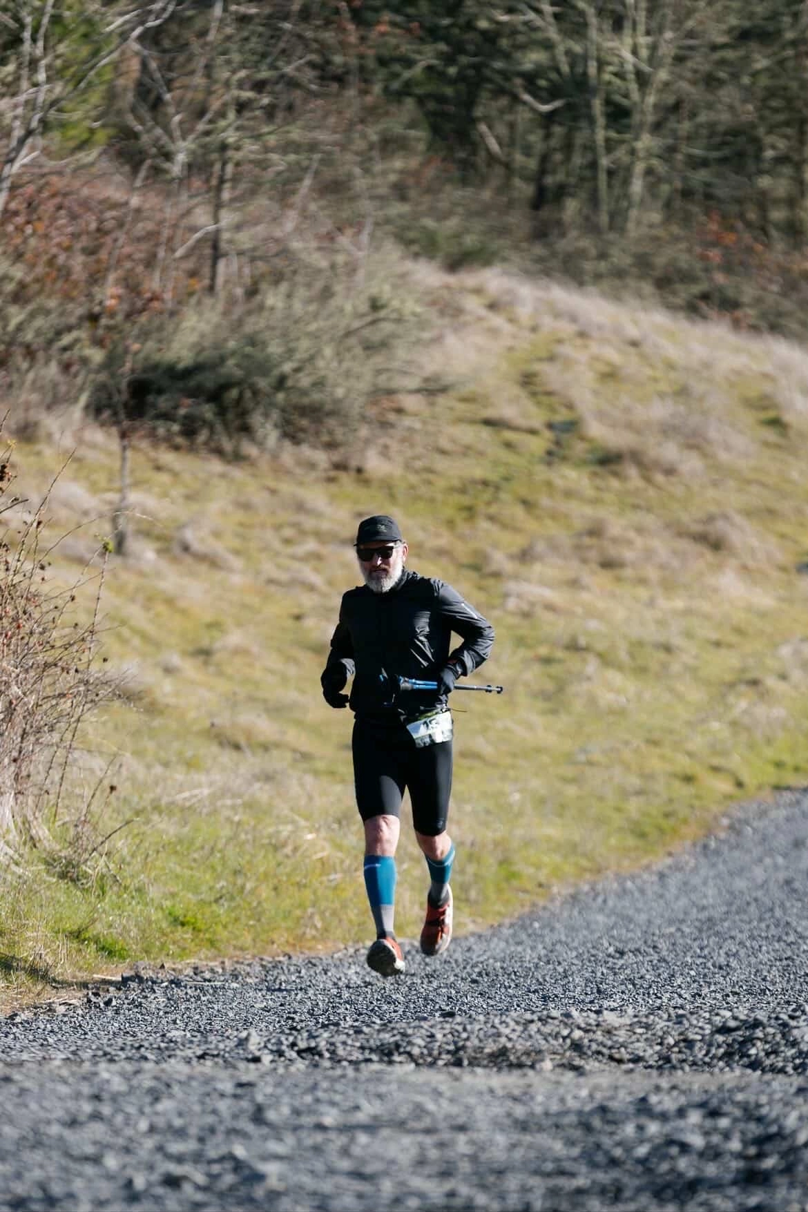 Trail runner jogging on gravel road through forested hillside
