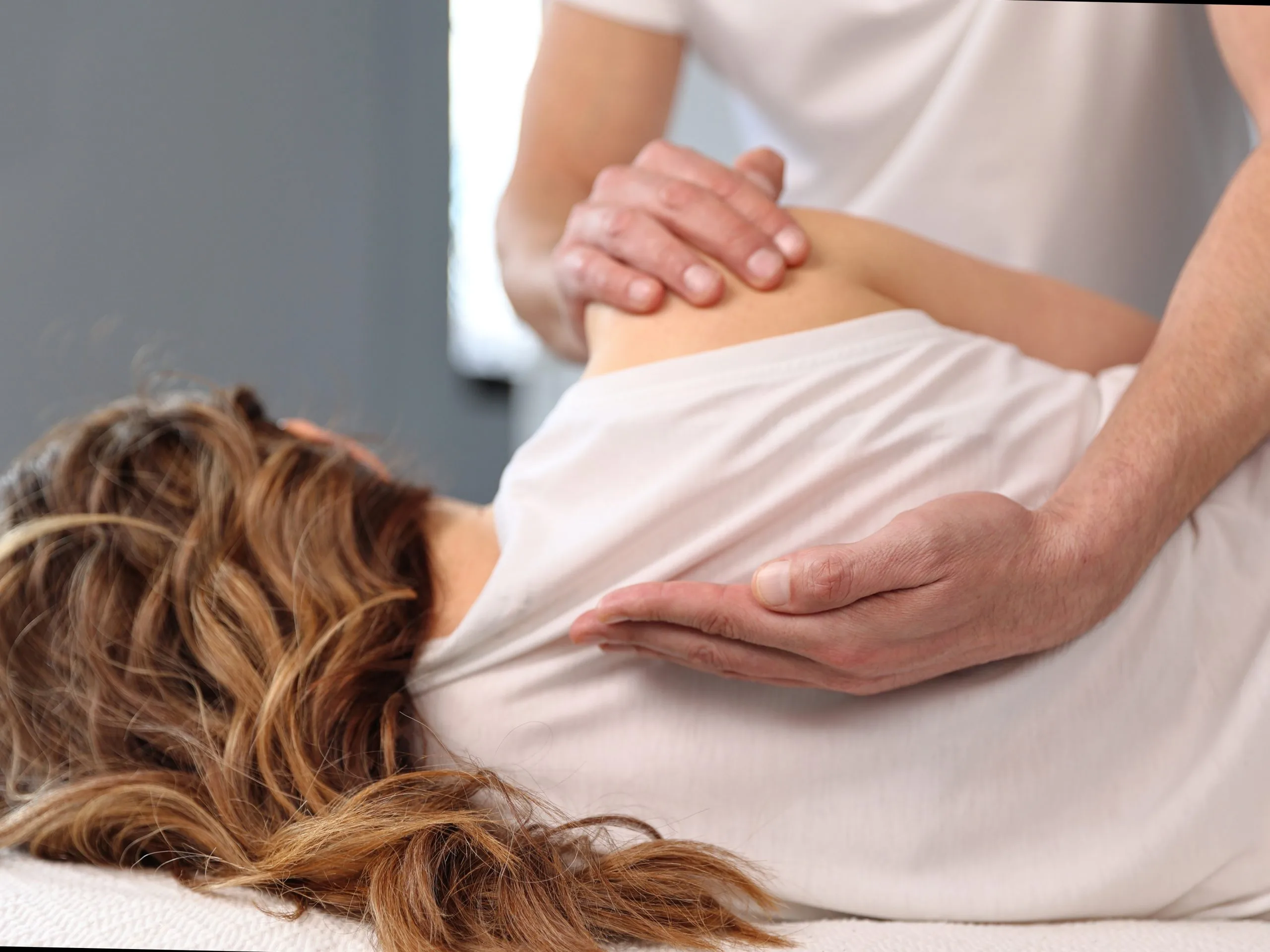 Therapist performing a shoulder or back massage on a client lying face down