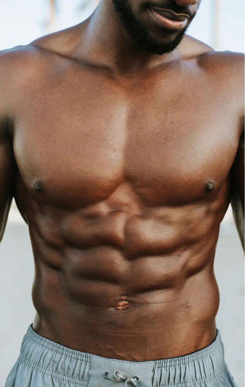 Shirtless man displaying defined chest and abdominal muscles with small scar visible on abdomen