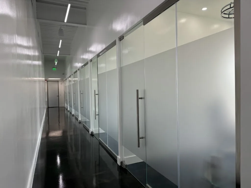 Interior hallway with treatment rooms lined with frosted glass partition walls
