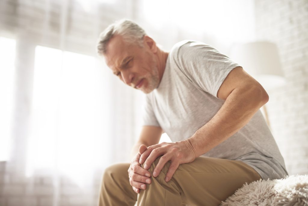 retired man pensioner suffering knee pain home scaled