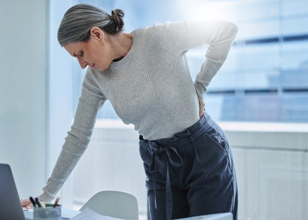 wheres chiropractor when you need one shot mature businesswoman standing alone office suffering from backache scaled