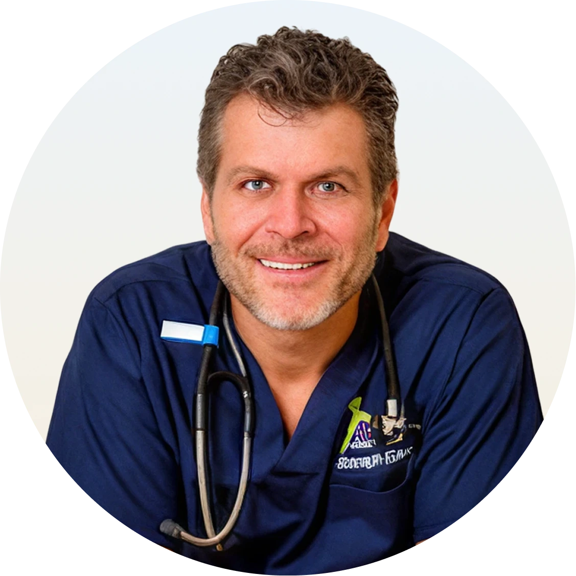 Joseph Gauta MD wearing navy scrubs and stethoscope, smiling at camera