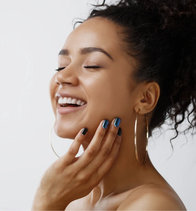 Woman smiling in profile with hand on chin, demonstrating facial volume and skin appearance