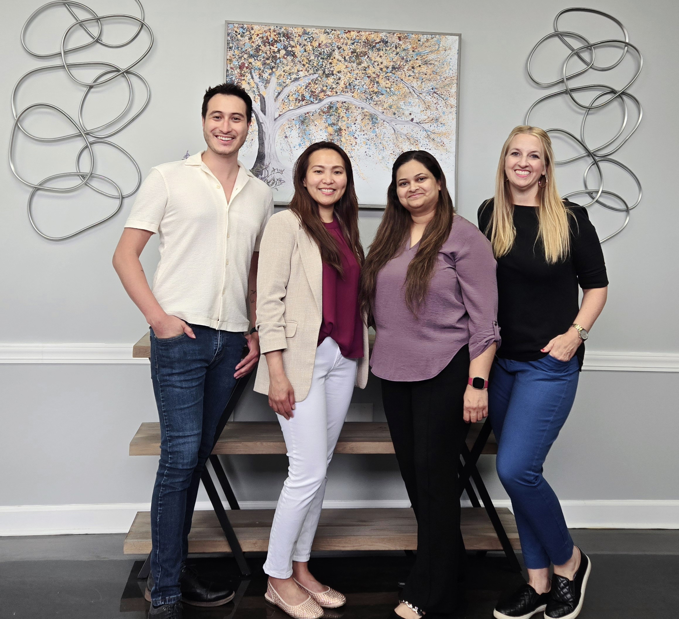 Four healthcare team members standing together in modern office with abstract wall art