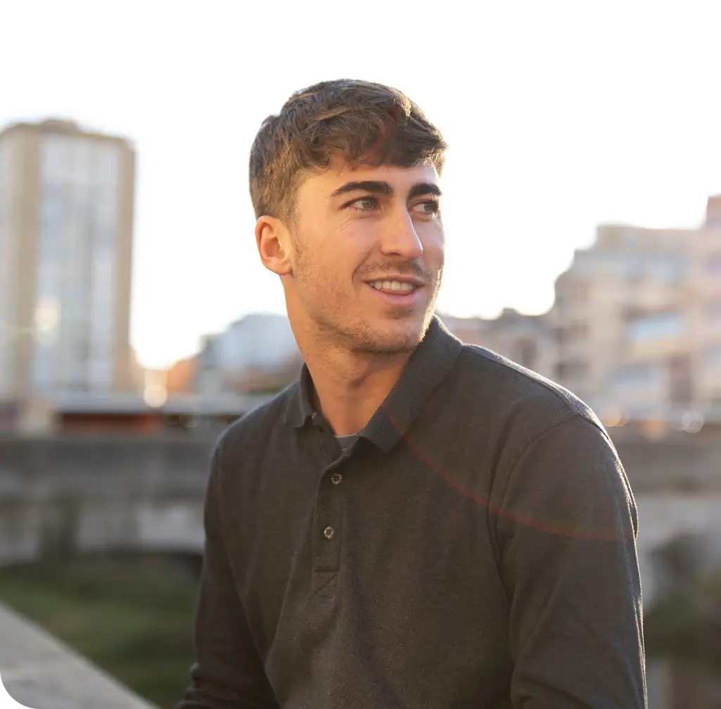 Man smiling outdoors with city buildings in background