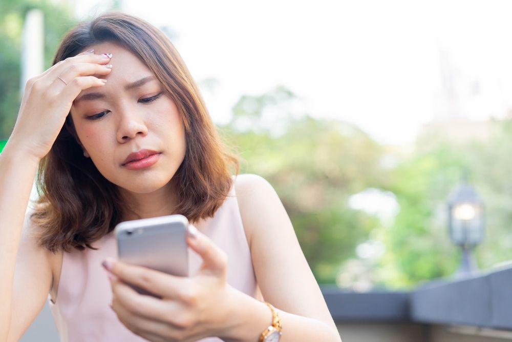 Woman looking stressed while holding a smartphone