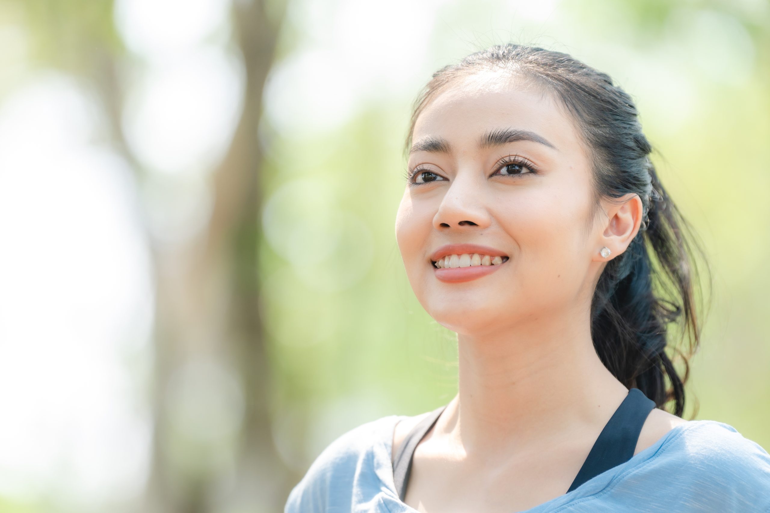 Woman smiling outdoors with a blurred green natural background