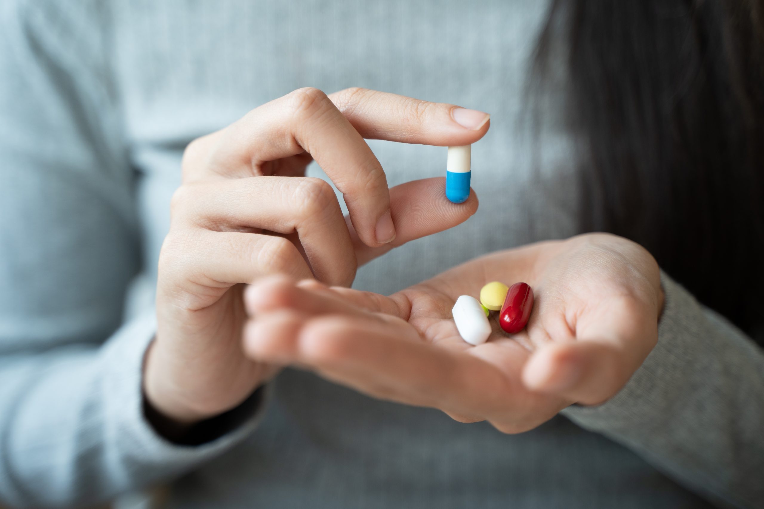 Person holding multiple medication capsules and pills in their palm