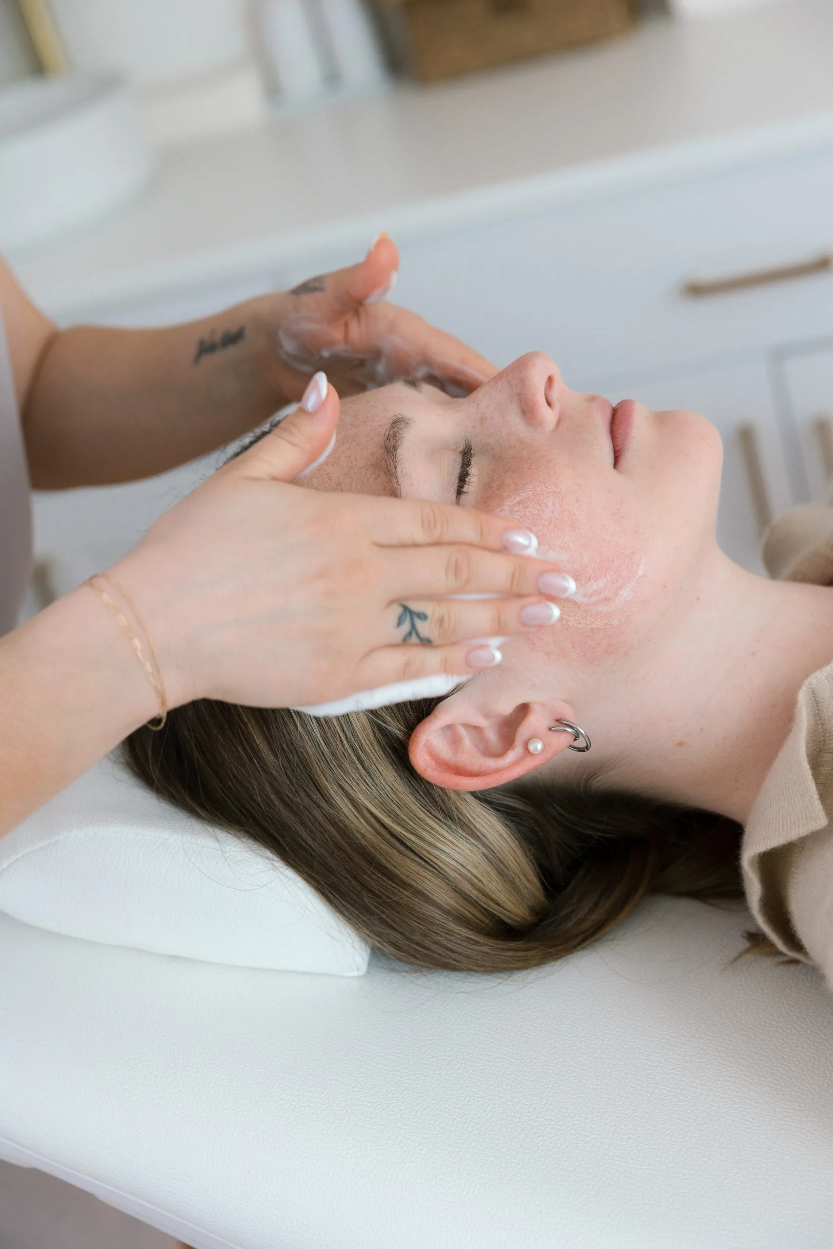 Esthetician massaging patient's face and forehead during facial treatment