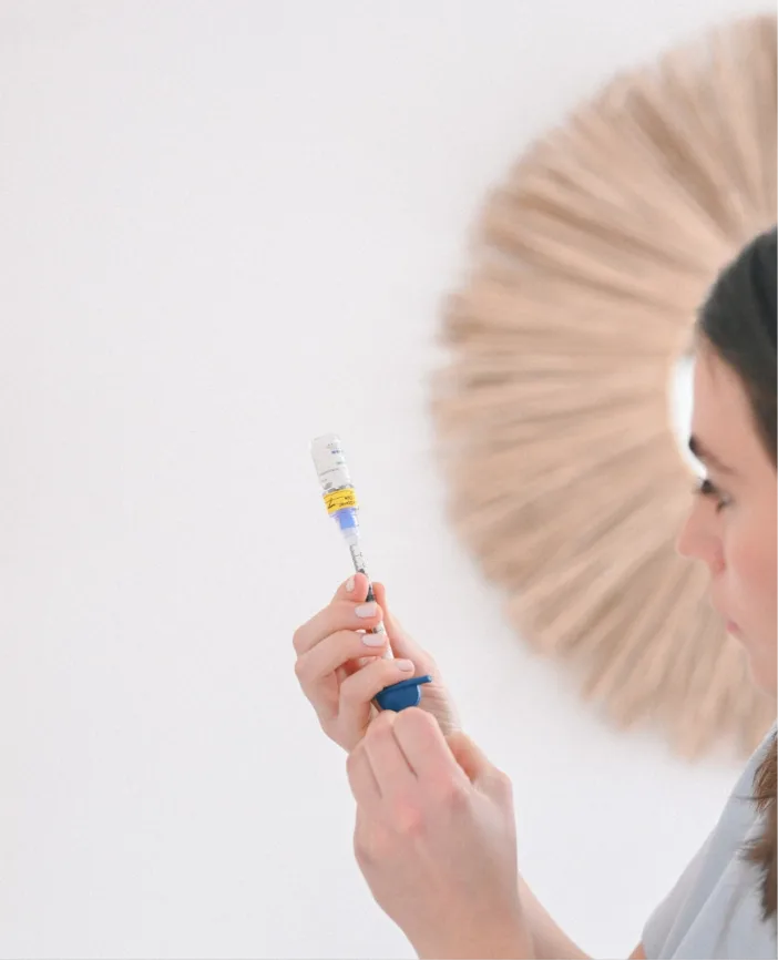 Practitioner holding a syringe with yellow label preparing for injectable treatment