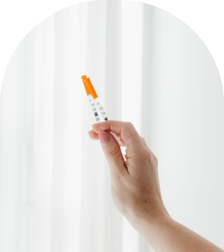 Hand holding Botox injection syringe with orange cap and measurement markings