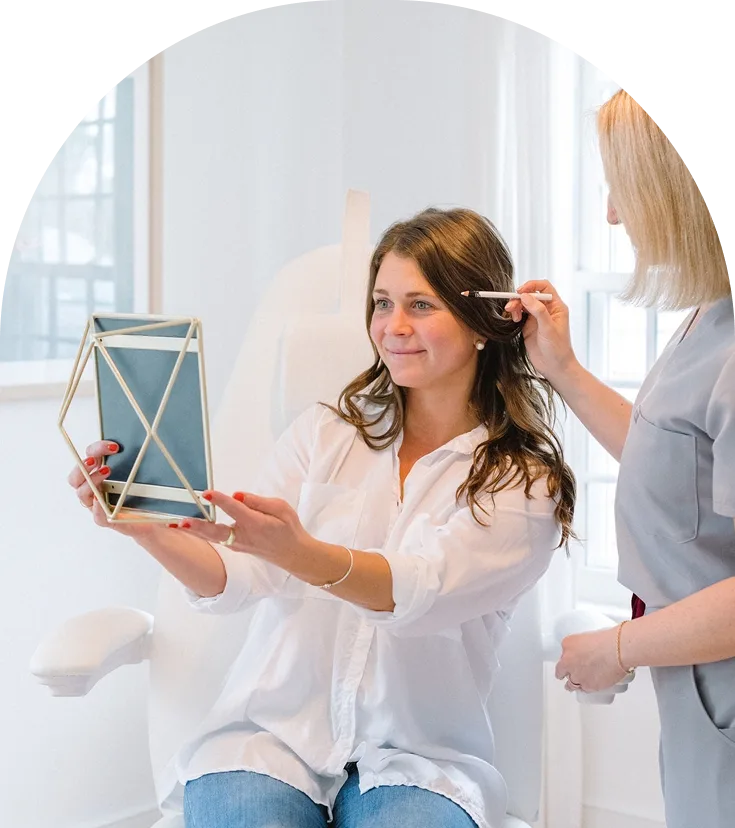 Practitioner examining patient's skin texture with handheld device during dermal filler consultation