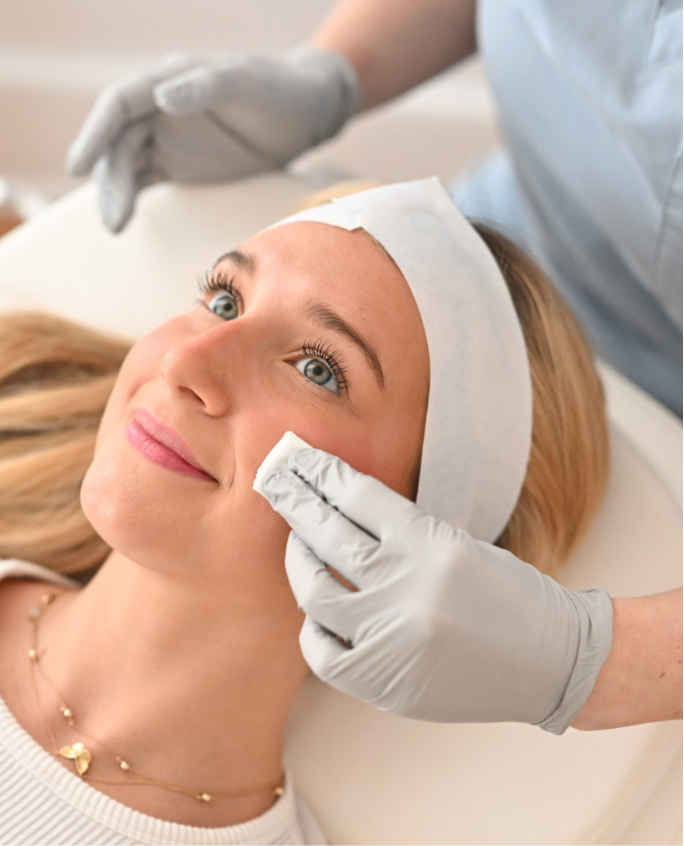 Gloved practitioner applying treatment to patient's cheek during facial