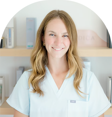 Healthcare provider in light blue scrubs smiling at camera in a clinical office setting