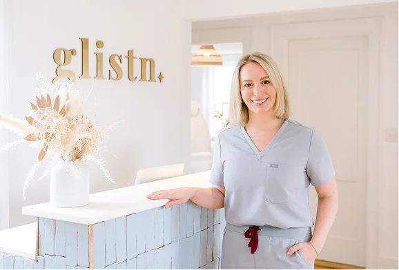 glistn. logo and clinician smiling at reception desk with white flowers