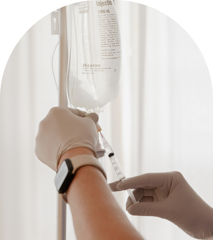 Healthcare provider administering IV drip infusion to patient's arm with Baxter injection bag