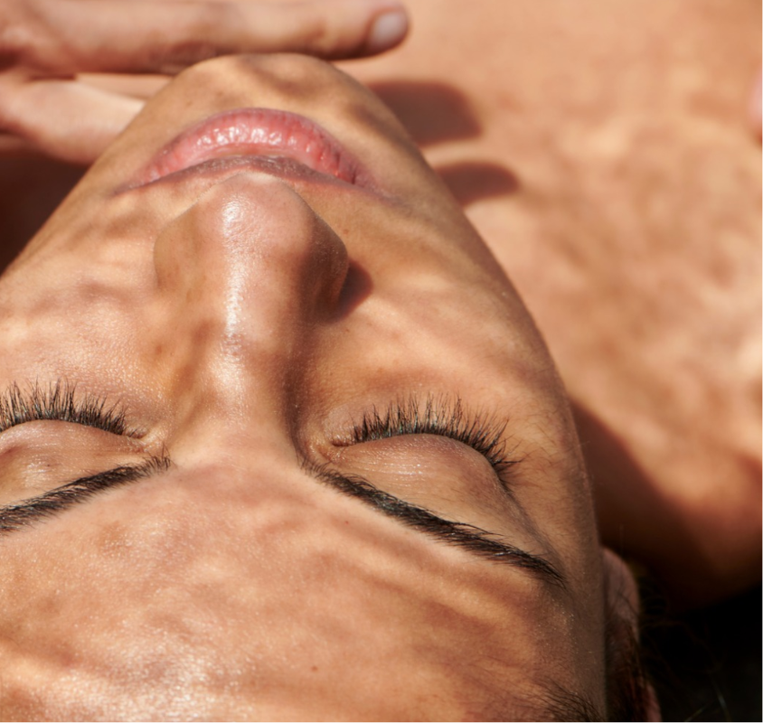 Close-up of person's face with eyes closed showing defined eyelashes and glowing skin