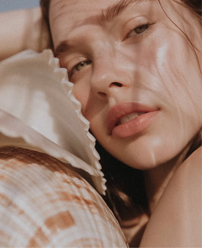 Woman holding soft fabric near face, displaying smooth, radiant complexion