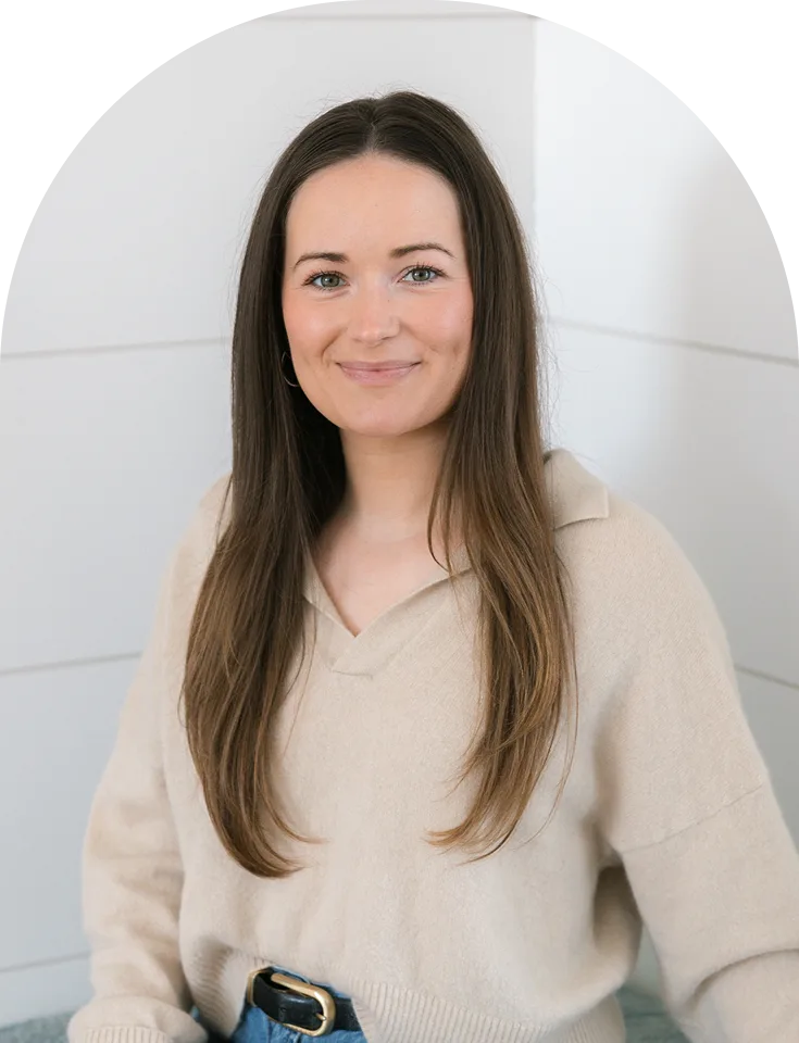 Woman with long brown hair in neutral expression, wearing cream v-neck sweater
