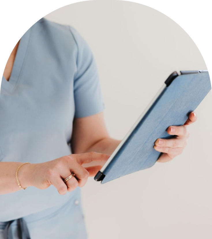 Healthcare provider in blue scrubs holding and reviewing a tablet device