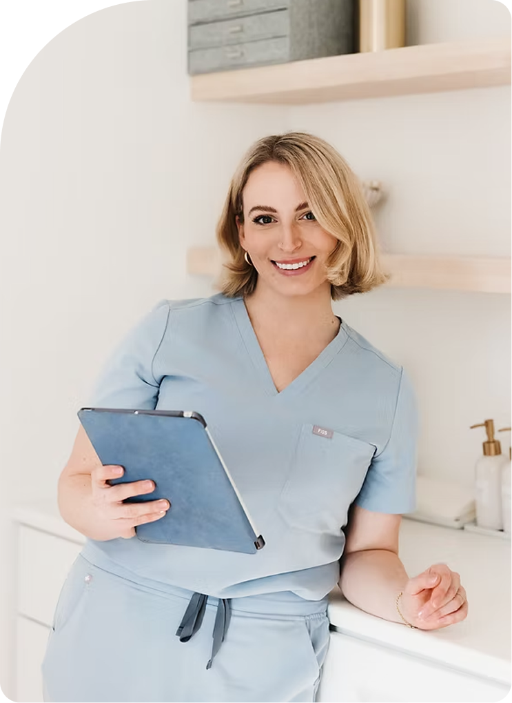 Healthcare provider in blue scrubs holding a tablet in a modern medical office