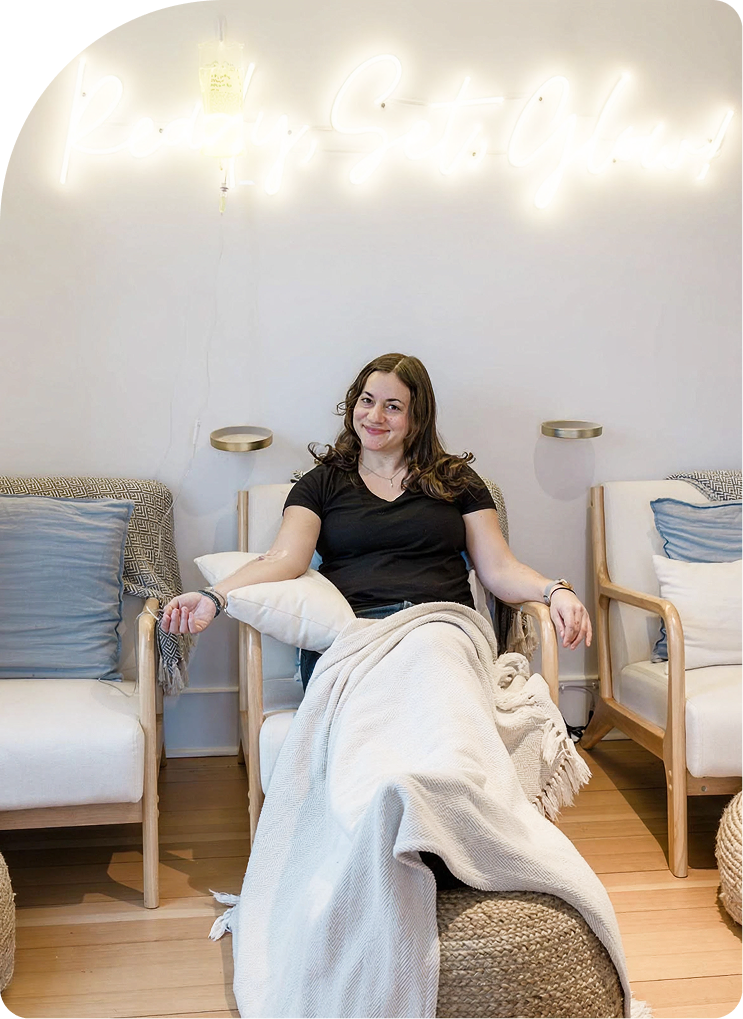 Woman relaxing in a modern wellness room with neon signage and comfortable seating