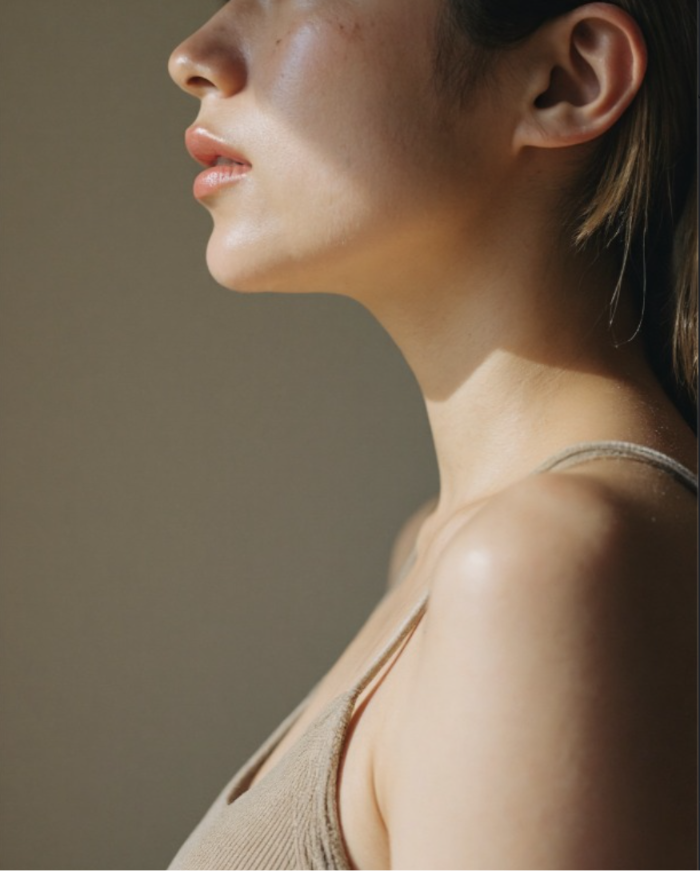 Woman shown in profile with clear, glowing skin and defined jawline
