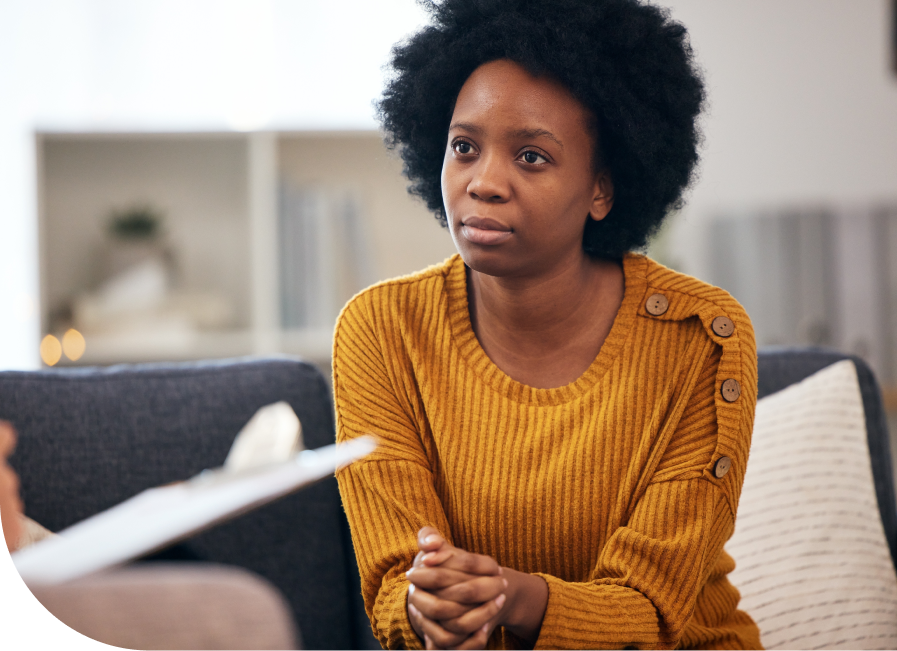 Woman in mustard sweater looking concerned during mental health counseling session with therapist