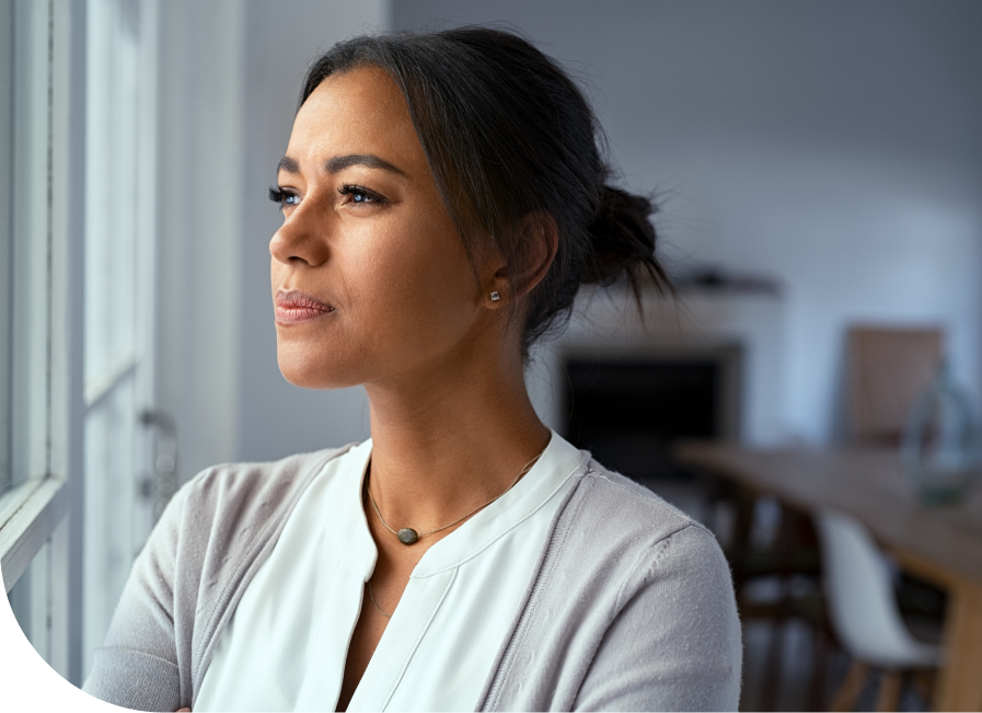 Woman gazing thoughtfully out a window in an indoor setting