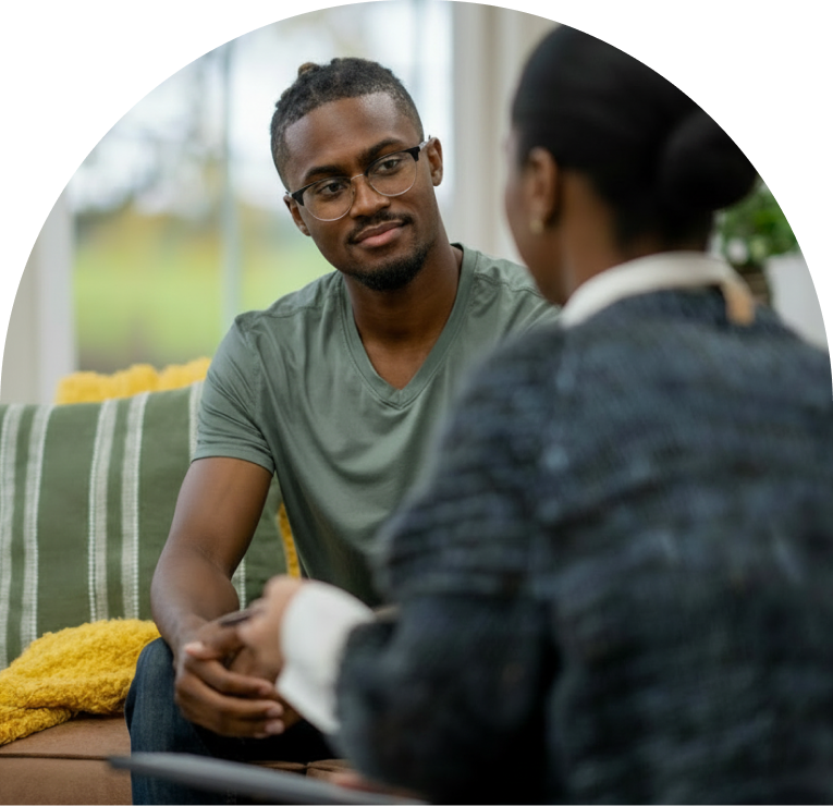 Man in glasses and green shirt speaking with a psychiatrist during a consultation in a bright clinical setting