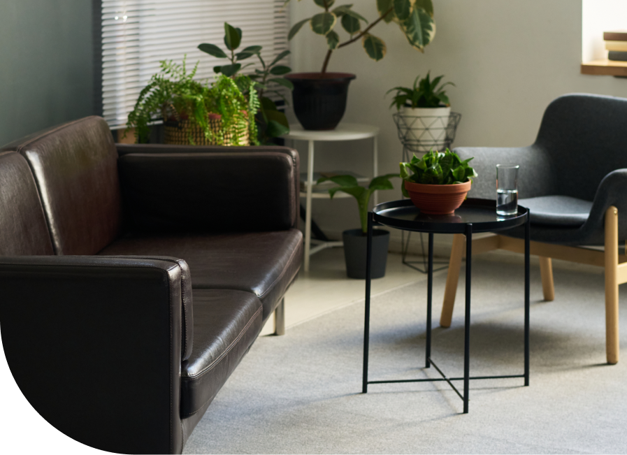 Modern waiting room with leather seating, potted plants, and round black side table