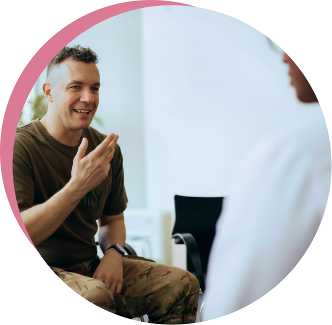 Man in olive shirt smiling and gesturing while speaking with healthcare provider in clinical setting
