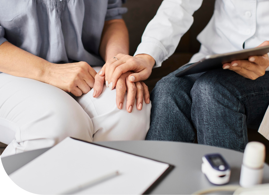 Healthcare provider and patient joining hands together during supportive psychiatric evaluation