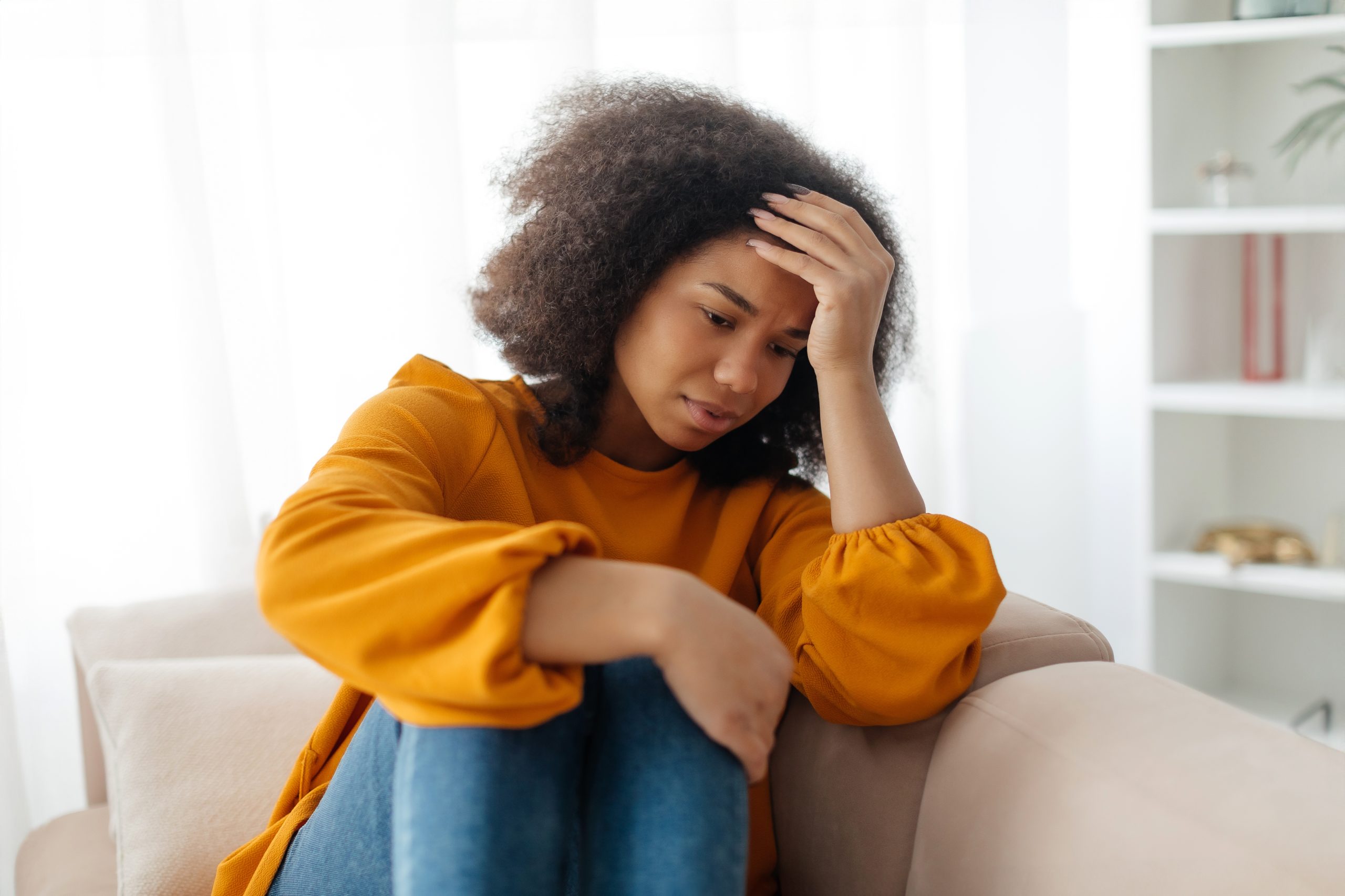 Depressedyoungafricanamericanwomansittingoncouchinthe