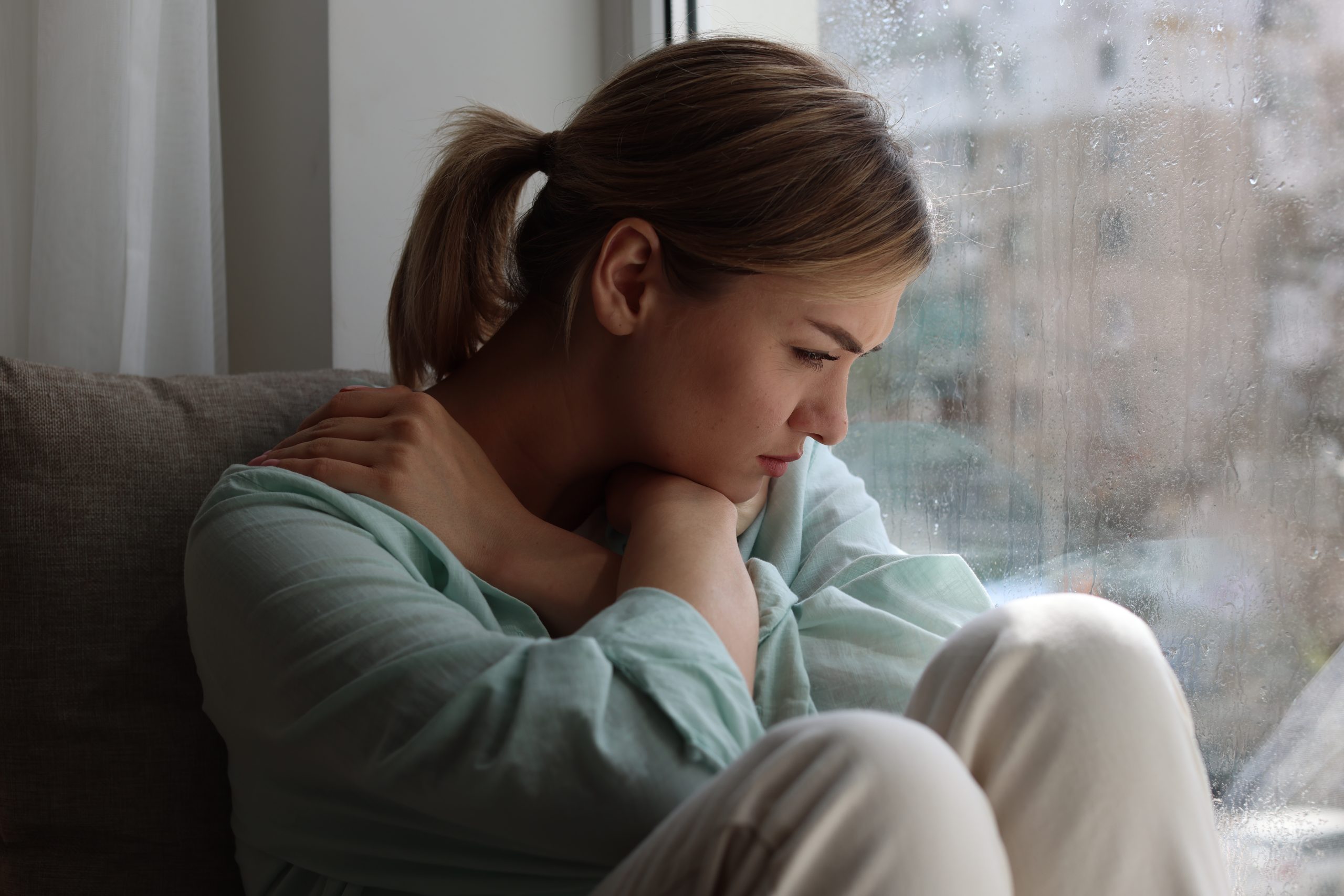 Depressedwomansittingnearwindowathome