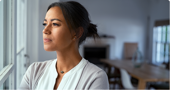 Woman gazing out a window in a bright indoor setting
