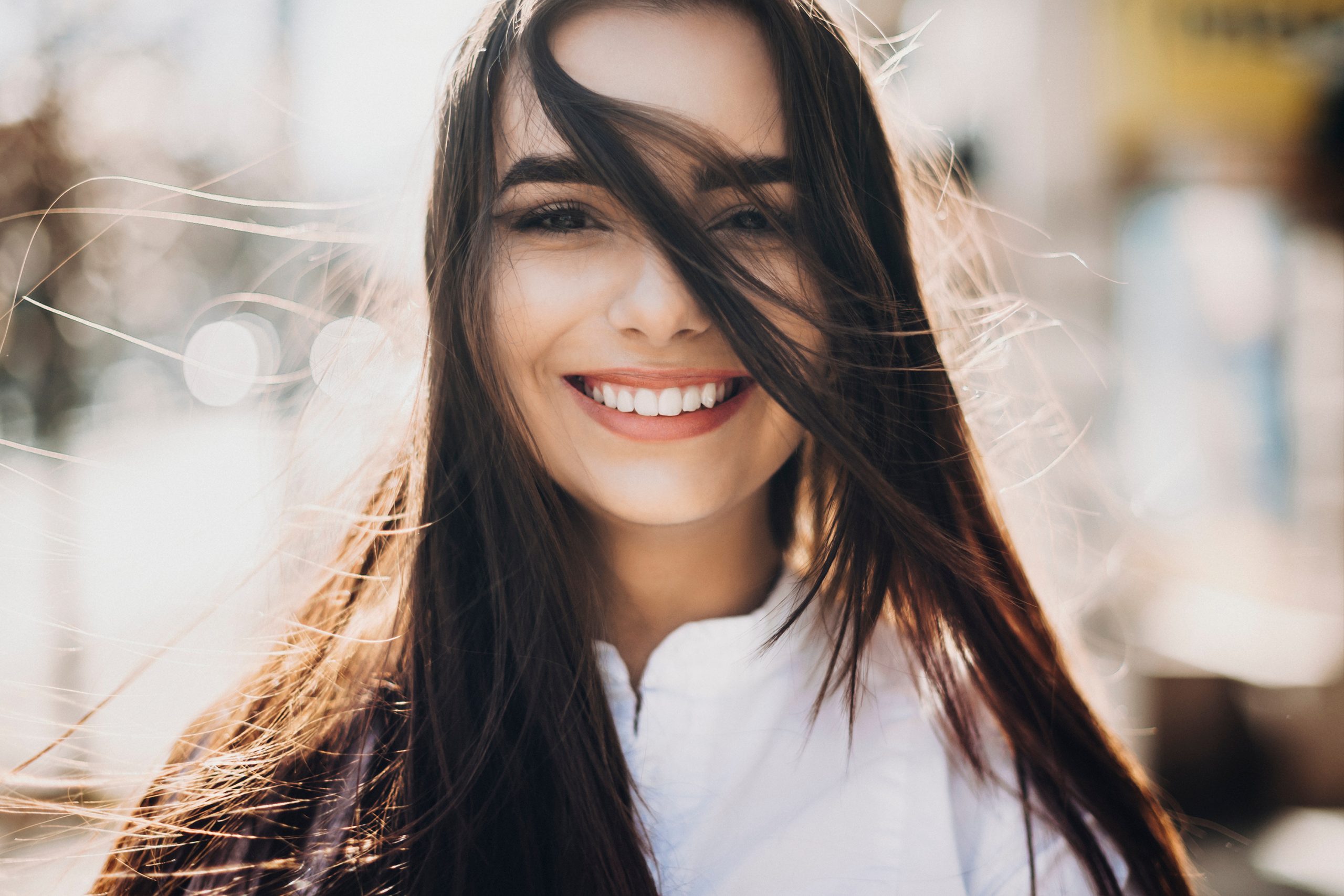 Woman with long dark hair smiling on an urban street