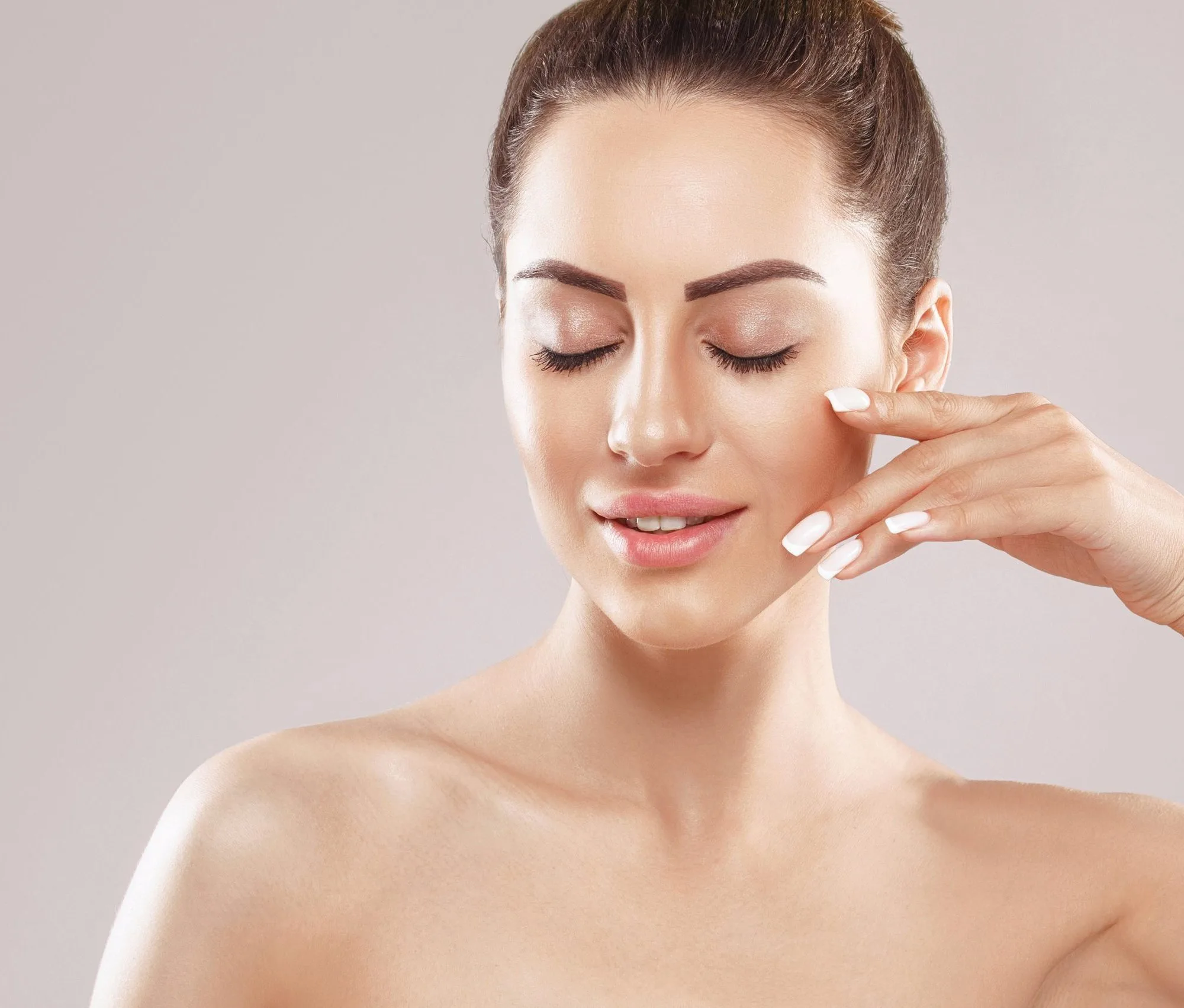 Woman applying skincare product to her cheek with fingertips