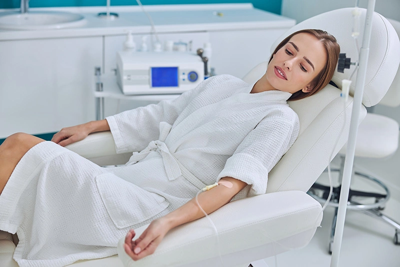 Patient resting in medical chair during IV therapy treatment in modern clinic