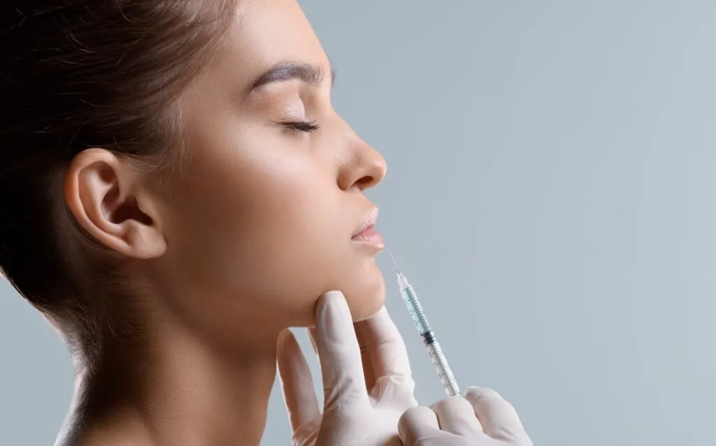 Close-up of syringe approaching woman's face for injection procedure