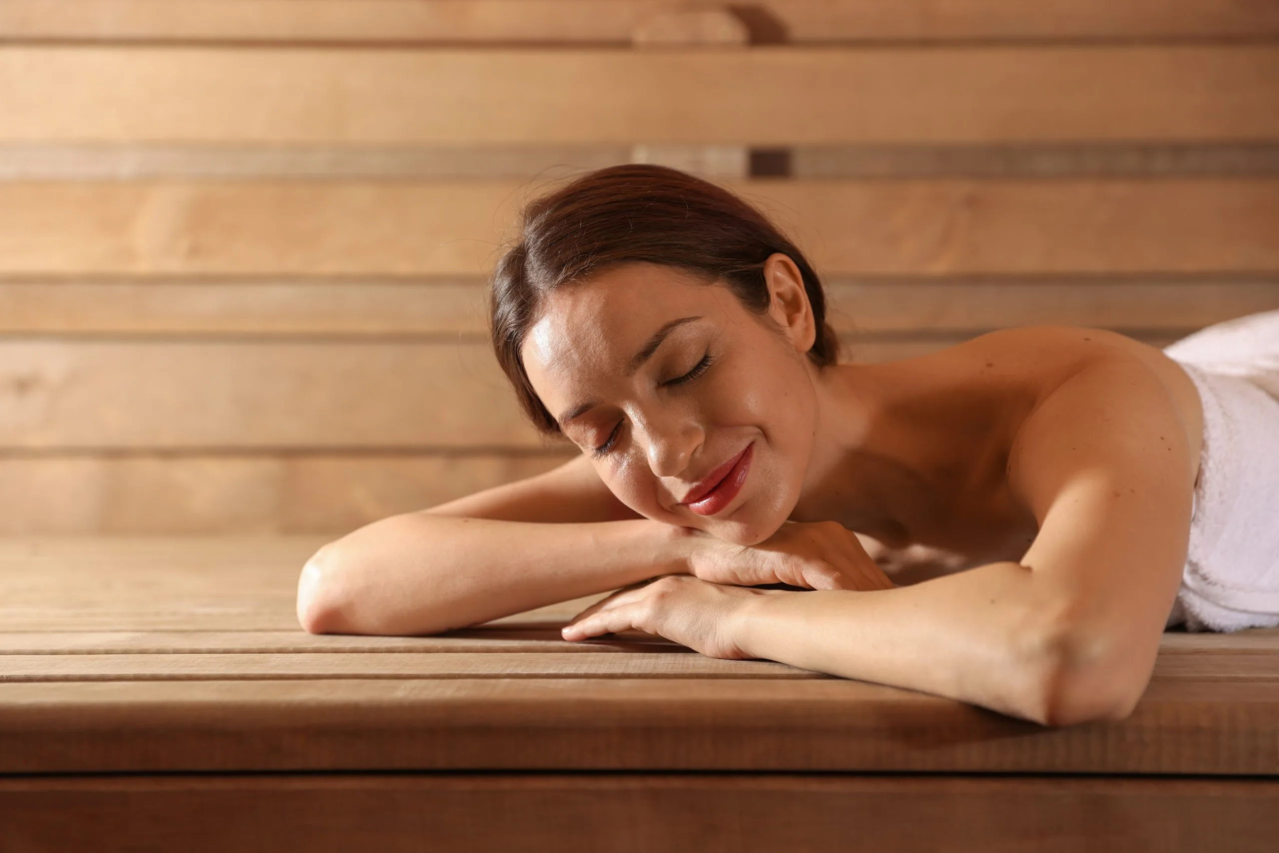 Woman relaxing face-down on wooden spa table with eyes closed