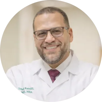 Emad Kandil, MD, MBA, smiling in white coat and burgundy tie