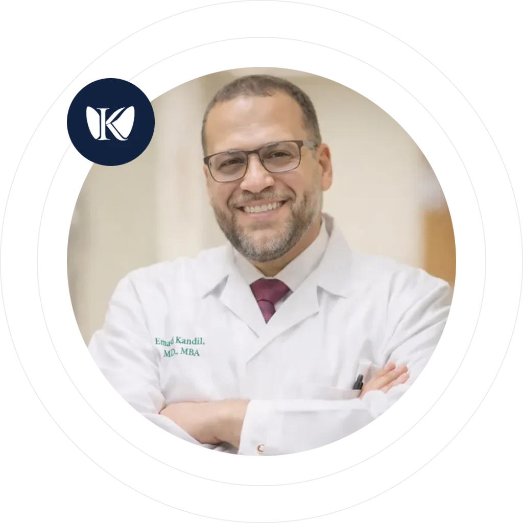 Dr. Emad Kandil, MD, MBA, wearing white coat and glasses with arms crossed