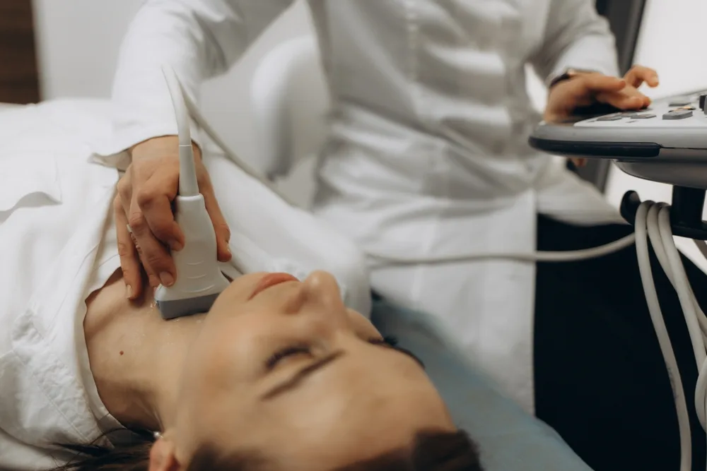 Physician using handheld ultrasound probe on patient's neck during examination