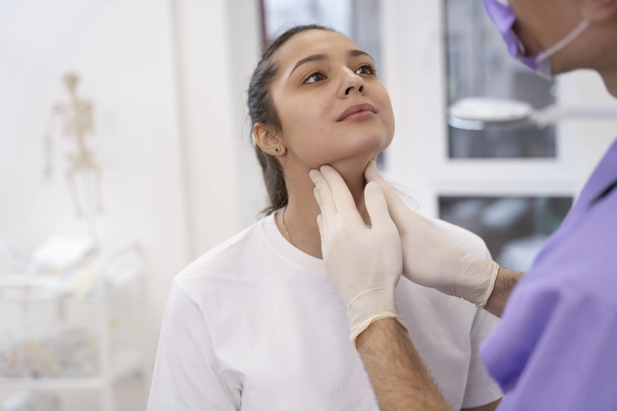 Doctor palpating patient's neck and thyroid area during physical examination