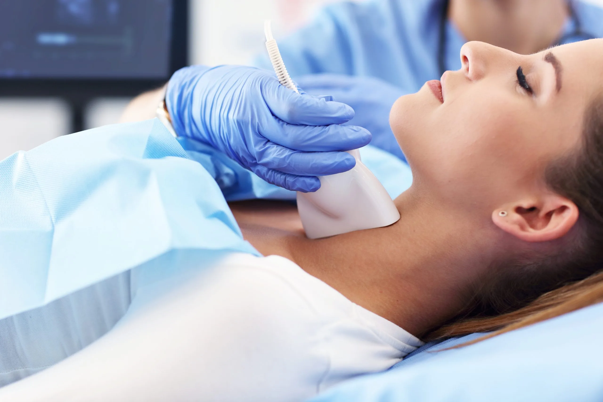 Practitioner in blue gloves performing ultrasound treatment on patient's chin during aesthetic procedure