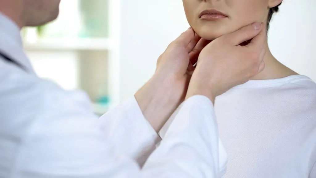 Doctor palpating patient's neck and throat during examination