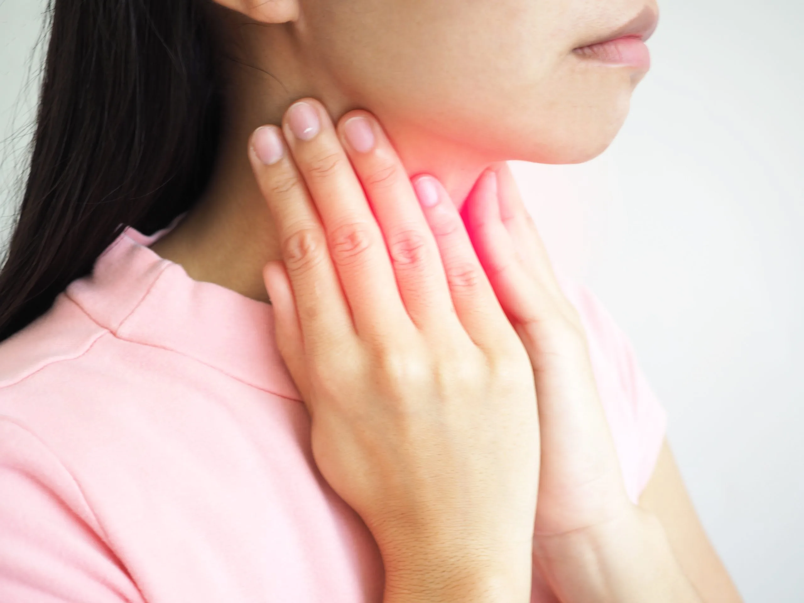 Woman holding her neck with red overlay indicating throat pain or swelling